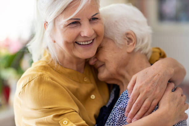Frau hält ältere Frau liebevoll im Arm