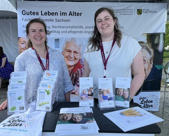 Zwei Mitarbeiterinnen am Informationsstand "Gutes Leben im Alter" mit Flyern und Materialien der Fachservicestelle Sachsen.