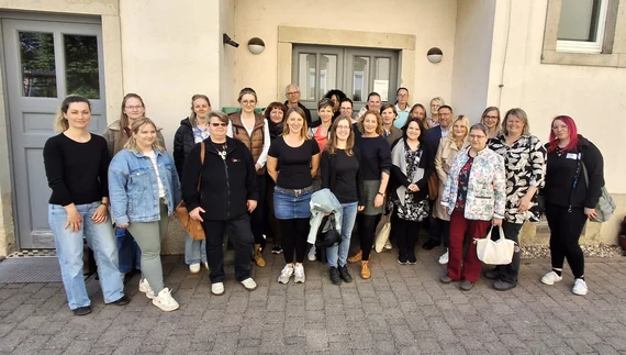 Gruppenfoto beim Nachbarschaftshilfe-Kontaktstellentreffen 2025 in Dresden vor Gebäudeeingang.