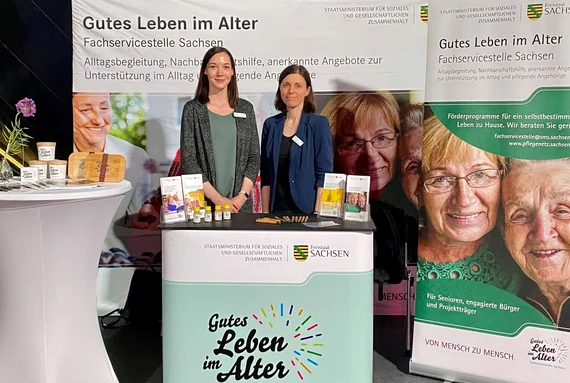 Zwei Mitarbeiterinnen am Stand der Fachservicestelle Sachsen „Gutes Leben im Alter" mit Informationsmaterial zu Alltagsbegleitung und Nachbarschaftshilfe.