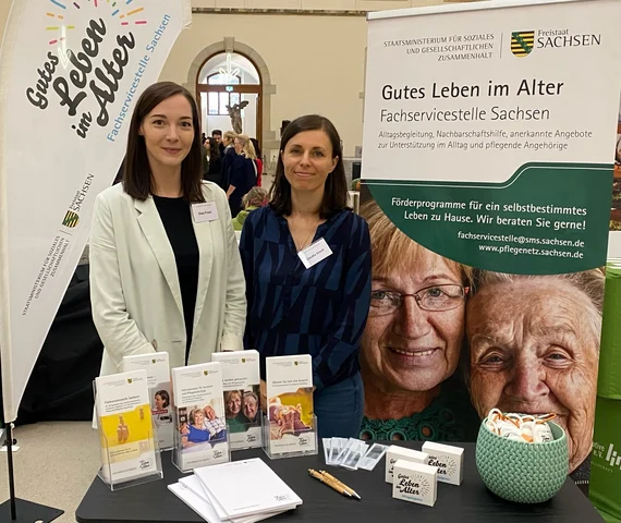 Zwei Mitarbeiterinnen am Stand der Fachservicestelle Sachsen „Gutes Leben im Alter" mit Informationsmaterial bei der Woche der Demenz 2024.